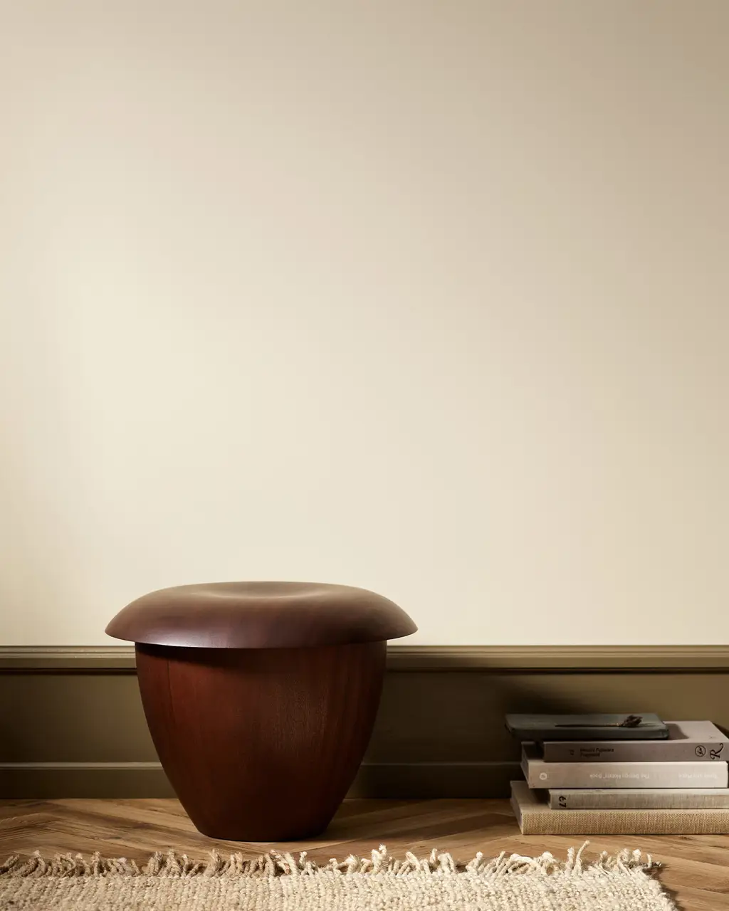 Wooden stool in a minimalist room with wall painted with Jotun 12313 Soft Dunes.