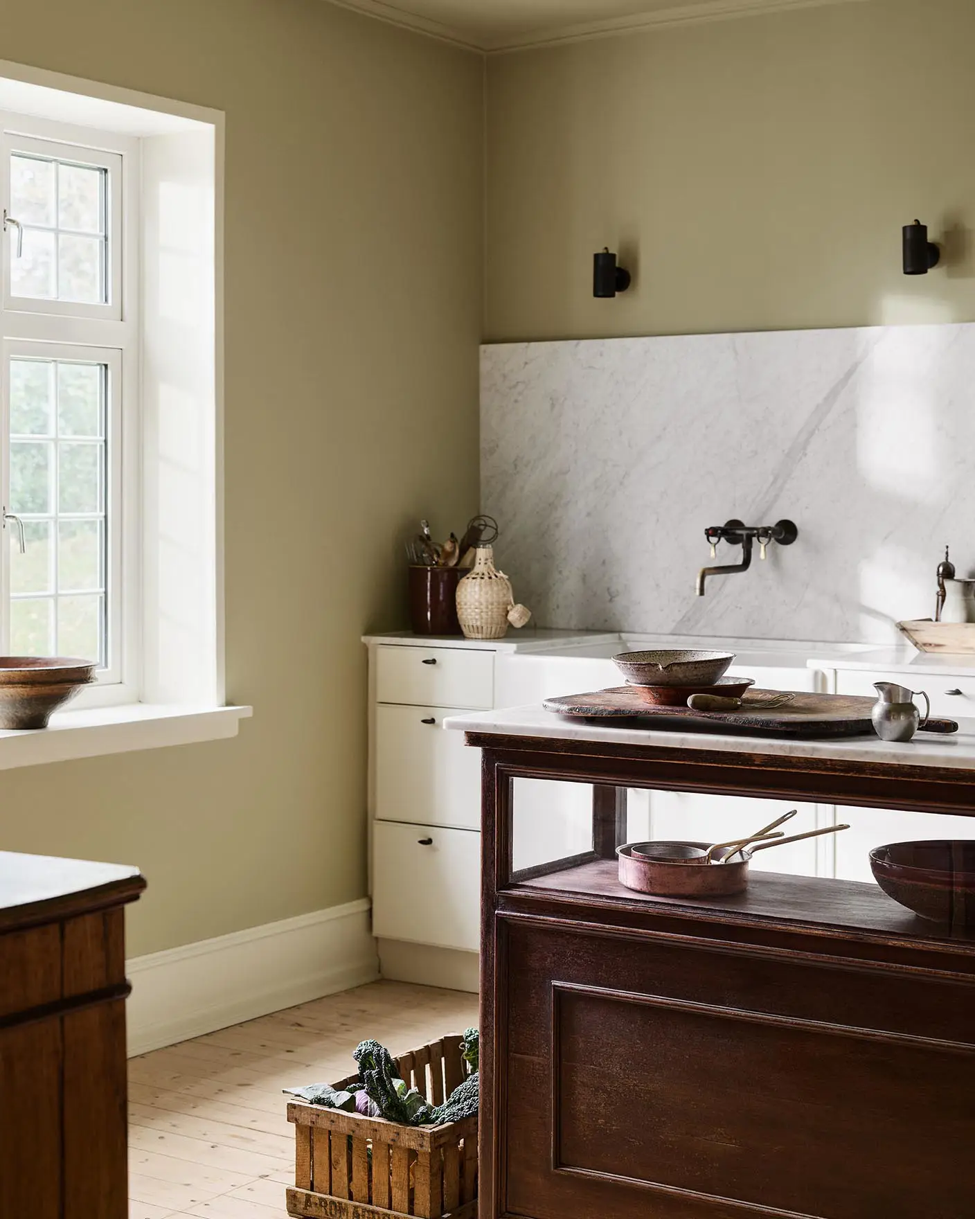 Kitchen with a marble backsplash, white cabins and a wooden island. Walls and ceiling painted with the Jotun colour 8284 Olive.