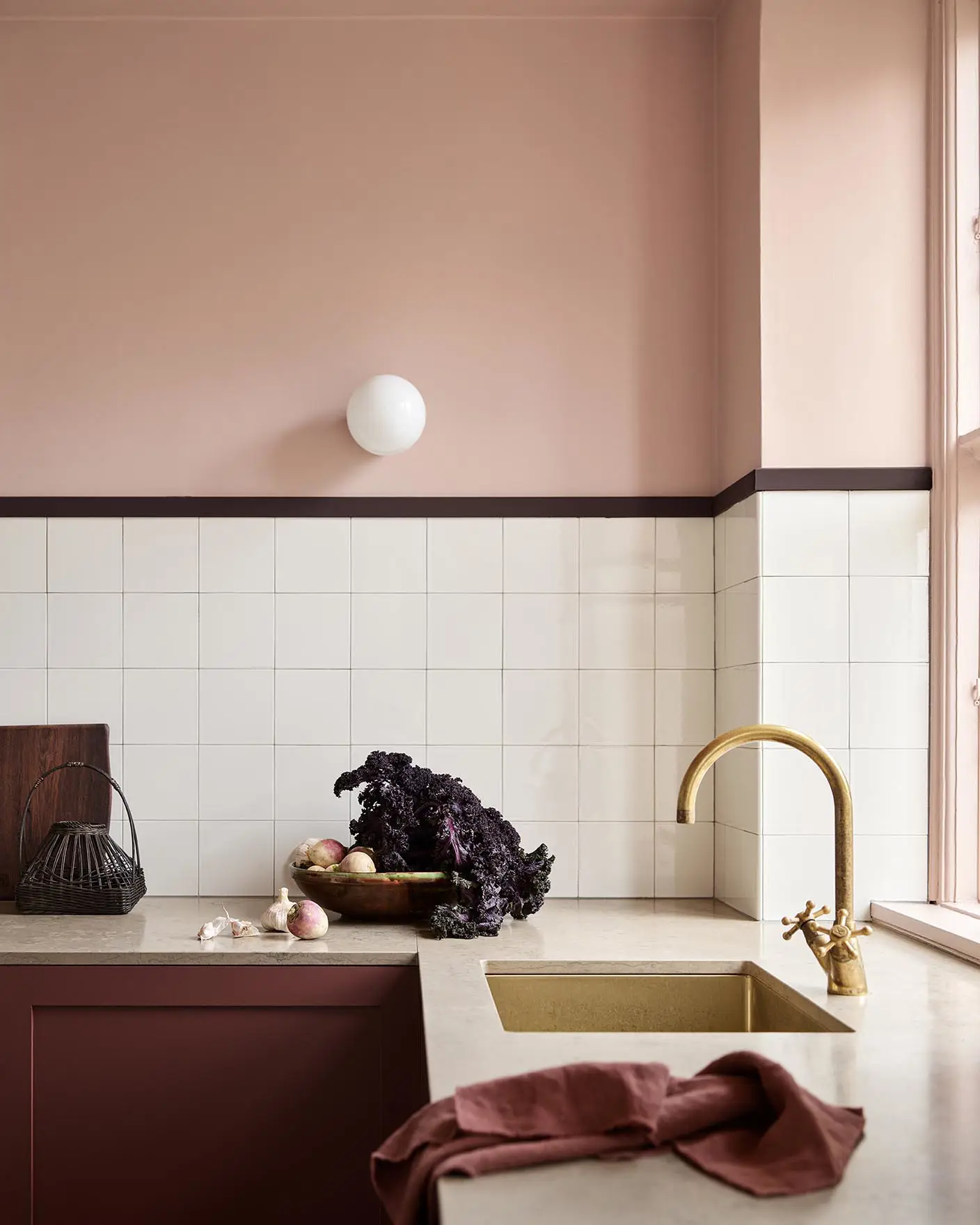 Kitchen counter with vegetables and decor against soft pink walls painted in the colour 20362 Pink Ambience from Jotun and white tile backsplash.
